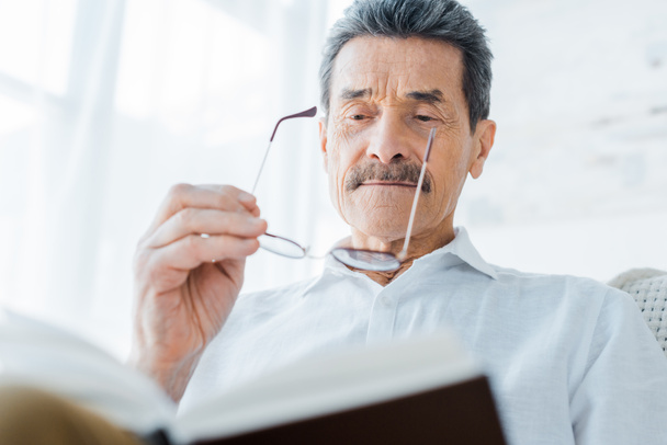 hombre mayor leyendo libro y usando gafas en casa
 - Foto, Imagen