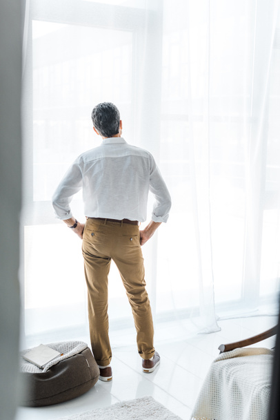 visão traseira do homem sênior em pé na casa moderna
 - Foto, Imagem