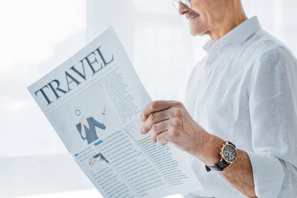 cropped view of senior man reading travel newspaper at home - Foto, Imagem
