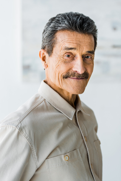 cheerful senior man with mustache looking at camera and smiling at home - Фото, зображення