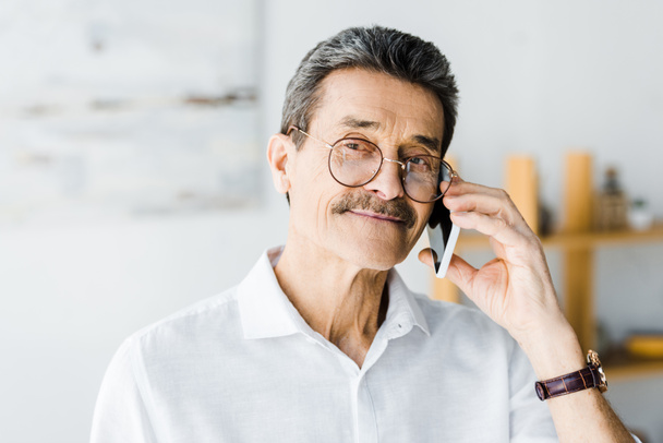 wesoły starszy człowiek w okularach rozmowy na smartfonie w domu - Zdjęcie, obraz