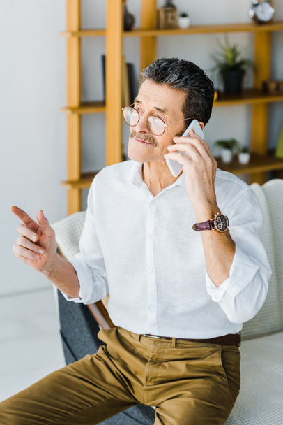  retired man in glasses talking on smartphone at home - Fotó, kép