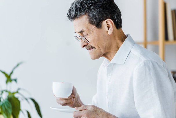 senior homme regardant tasse avec café à la maison
 - Photo, image