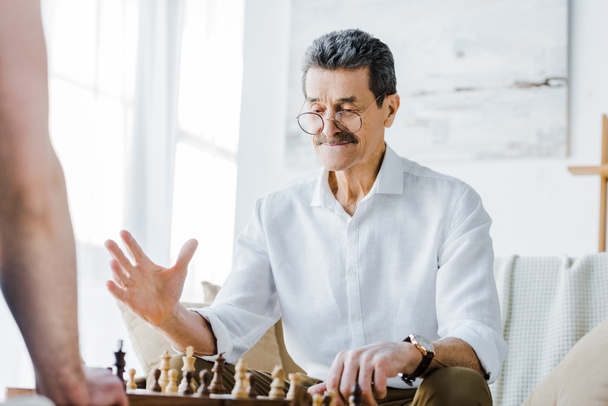 selektywne focus starszy mężczyzna z wąsem, gra w szachy z przyjacielem w domu - Zdjęcie, obraz