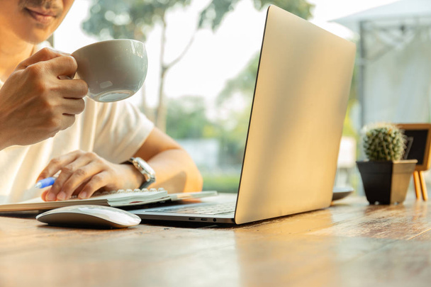 Podnikatel pracovat na stoly ruce drží pohár coffeewith laptop na stole - Fotografie, Obrázek