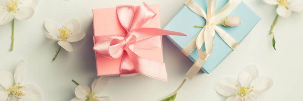 two gifts surrounded by Apple white flowers. blue and pink presents. gentle background top view - Foto, afbeelding