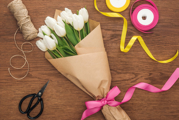 felülnézet tavaszi tulipán csokor, szalagok és a kézműves papír, fából készült háttér  - Fotó, kép