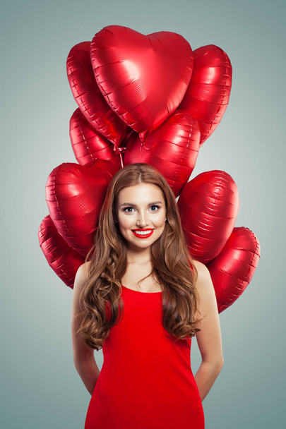 Holčička s balónky srdce. Žena s červenými rty make-up nosí v červených šatech. Valentines lidí a den svatého Valentýna koncepce  - Fotografie, Obrázek
