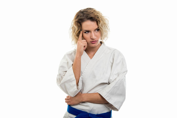 Портрет жінки у формі бойових мистецтв робить жест мислення ізольованим на білому тлі
 - Фото, зображення
