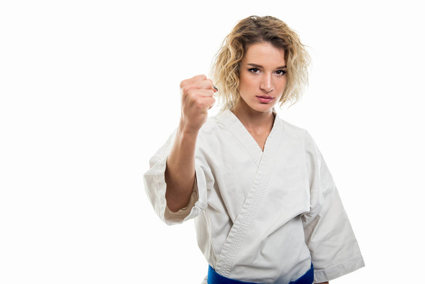 Porträt einer Frau in Kampfsportuniform, die Faust wie Kampf isoliert auf weißem Hintergrund mit Kopierraum-Werbefläche zeigt - Foto, Bild