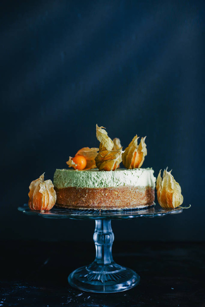 Matcha cheesecake presented with some alkekengi fruit against a dark background - Foto, afbeelding