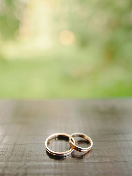 Wedding rings on green background and wooden surface with copy space - Valokuva, kuva