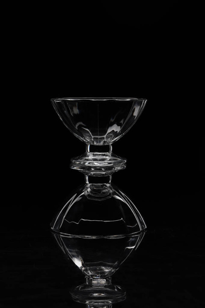 two transparent glass vases on top of each other on a black background and their reflection - Photo, image