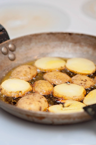 ジャガイモだ！フィンランドのキッチンでフランスのミネラルフライパンにオリーブオイルでゆでたジャガイモを炒めることによる誘導料理 - 写真・画像