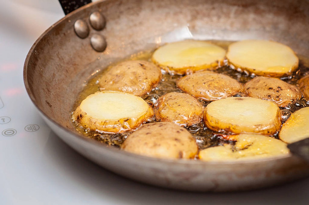 Batatas fritas! Cozinhar por indução fritando batatas cozidas em azeite em uma frigideira mineral francesa em uma cozinha finlandesa
 - Foto, Imagem