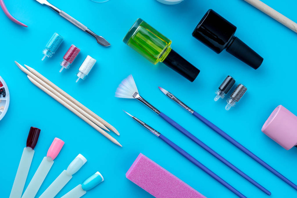 A set of cosmetic tools for professional manicure, nail care and to create beautiful designs on a blue background - Zdjęcie, obraz