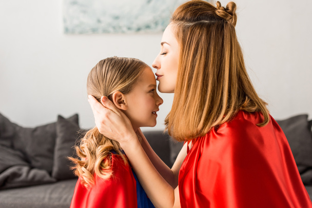 Beautiful mother kissing cute daughter at home  - Photo, Image
