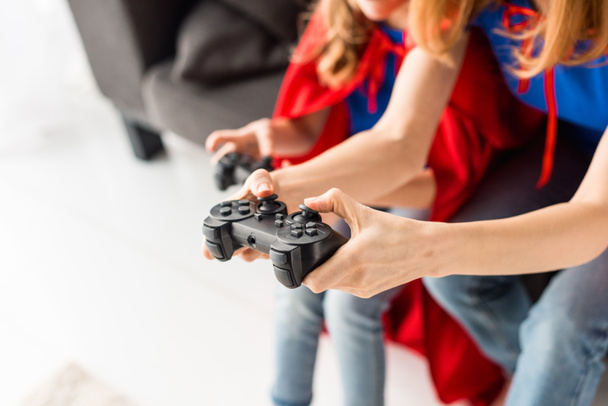 Részleges kilátás a nő és a gyerek játszik otthon a videó-játék - Fotó, kép