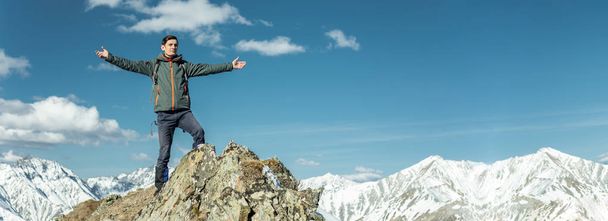 Los hombres turistas celebran el éxito extendiendo sus brazos sobre el fondo de las montañas nevadas en un día soleado. El concepto de motivación y logro de sus objetivos
 - Foto, imagen