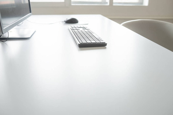 Низький кут огляду офісного комп'ютера - монітор, миша і клавіатура, на білому офісному столі
. - Фото, зображення