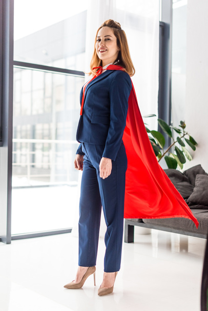 businesswoman in blue suit and red cape looking at camera - Foto, Bild