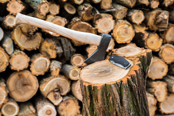 axe and jackknife case on the stump, firewoods on the background - Photo, Image