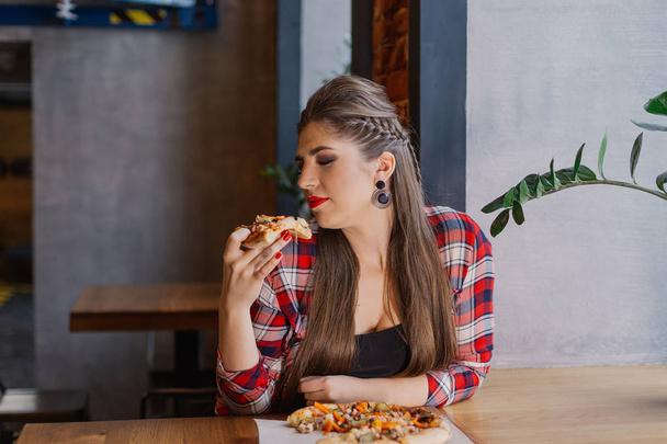 Bir kafede cam kenarında oturan ve pizza yemek güzel ve seksi kız. - Fotoğraf, Görsel