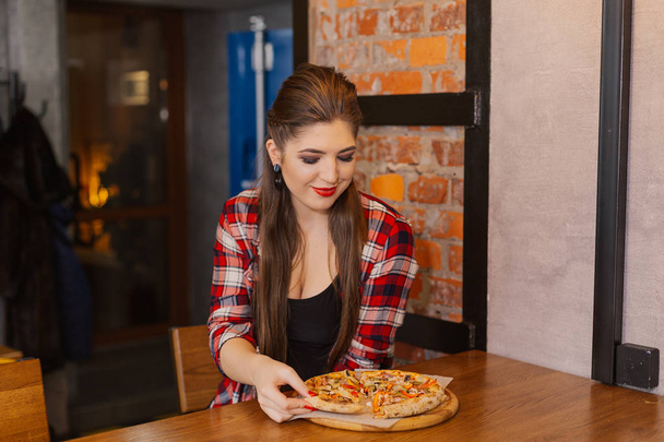 カフェの窓辺に座っていると、ピザを食べて美しく、セクシーな女の子. - 写真・画像