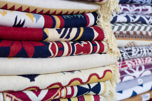 Ράφια με κρεβάτι καλύπτει στοίβες στο κατάστημα. Σωρούς από πολύχρωμες κουβέρτες στα ράφια των καταστημάτων. - Φωτογραφία, εικόνα