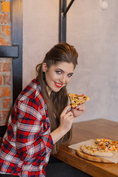 Beautiful and sexy girl sitting at a table with a pizza in a cafe. - Foto, immagini