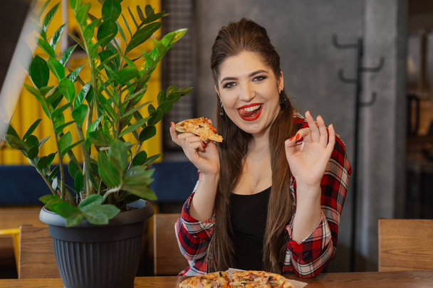 Belle et sexy fille assise à une table avec une pizza dans un café
. - Photo, image