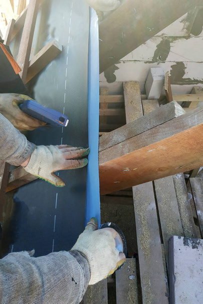 Arbeiter wärmen Dach unter der Dachfolie 2019 - Foto, Bild