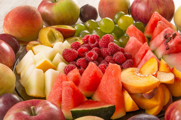 Gyümölcs mix. Őszibarack, szőlő, alma, görögdinnye, sárgadinnye, málna, szilva. Zamatos, és érett darab gyümölcs közelről. - Fotó, kép