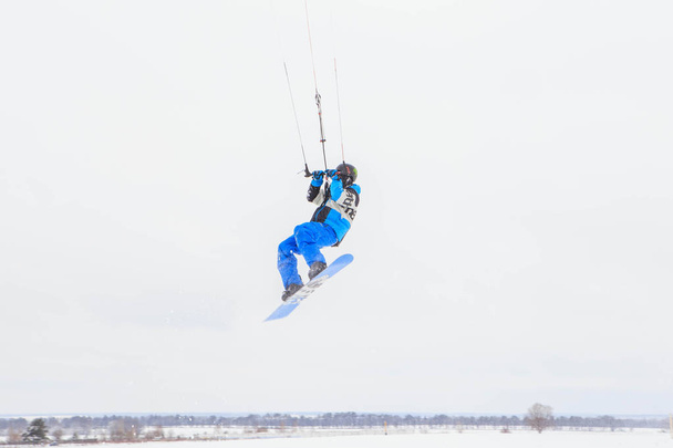 Молода жінка в блакитному зимовому одязі і шоломі катається на сноуборді вдень
 - Фото, зображення
