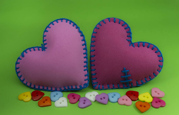 herzförmige handgenähte Textilherzen aus rosa Stoff und mit blauen Fäden auf grünem Chromakey-Hintergrund genäht für romantische oder valentine Konzepte - Foto, Bild