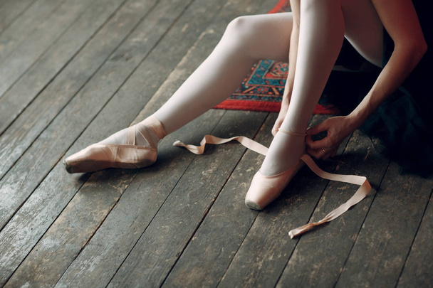 Bailarina prepárate para la actuación. Joven hermosa bailarina de ballet, vestida con traje profesional, zapatos puntiagudos y tutú negro
. - Foto, imagen