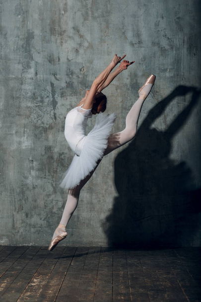 Bailarina saltando. Joven hermosa bailarina de ballet, vestida con traje profesional, zapatos puntiagudos y tutú blanco
. - Foto, Imagen