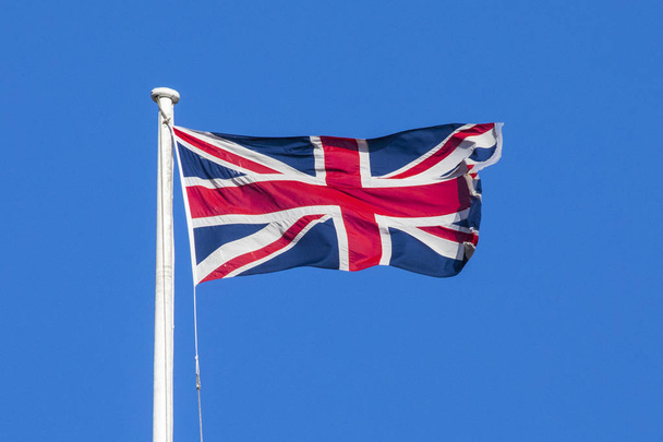 A view of a Union flag flying over a clear blue sky. - Foto, imagen