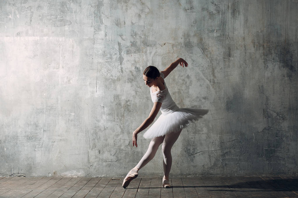 Ballerina weiblich. junge schöne Balletttänzerin in professionellem Outfit, Spitzenschuhen und weißem Tutu. - Foto, Bild