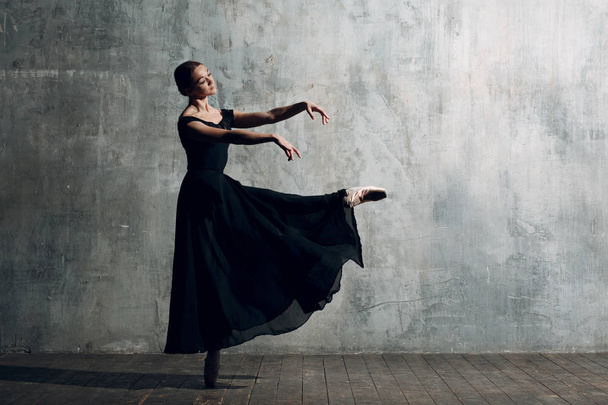 Női balerina. Profi felszerelés, a pointe cipők és a fekete ruhában öltözött fiatal gyönyörű nő balett-táncos. - Fotó, kép