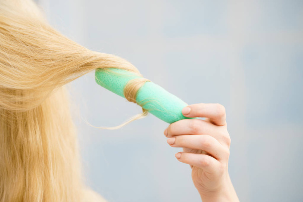 Blonde woman using hair rollers to create beautiful hairstyle on her hairdo. - Fotoğraf, Görsel