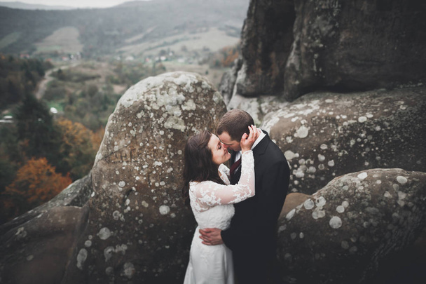 Happy wedding couple posing over beautiful landscape in the mountains - Valokuva, kuva