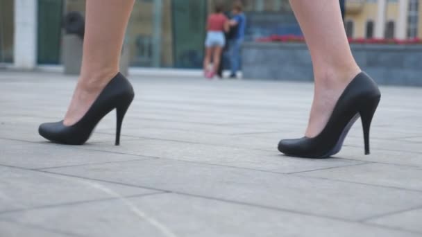 Piedi di donna d'affari giovane in calzature su tallone alto che va in strada urbana. Slim gambe femminili in scarpe nere sui tacchi alti che camminano sulla città. Ragazza che va al lavoro. Vista ad angolo basso Movimento lento Avvicinamento - Filmati, video