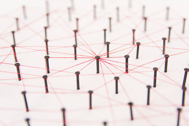 Entidades vinculantes, redes sociales, red de comunicaciones, la conexión entre las dos redes. Simulación de red sobre papel blanco enlazado creado por clavo negro e hilo rojo
 - Foto, imagen