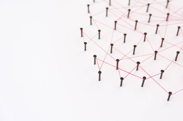 Entidades vinculantes, redes sociales, red de comunicaciones, la conexión entre las dos redes. Simulación de red en papel blanco enlazado creado por clavo negro e hilo rojo con espacio de copia
 - Foto, imagen