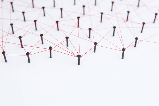 Verknüpfung von Einheiten, sozialen Medien, Kommunikationsnetzen, die Verbindung zwischen den beiden Netzwerken. Netzwerksimulation auf weißem Papier, verbunden durch schwarzen Nagel und roten Faden mit Kopierraum - Foto, Bild