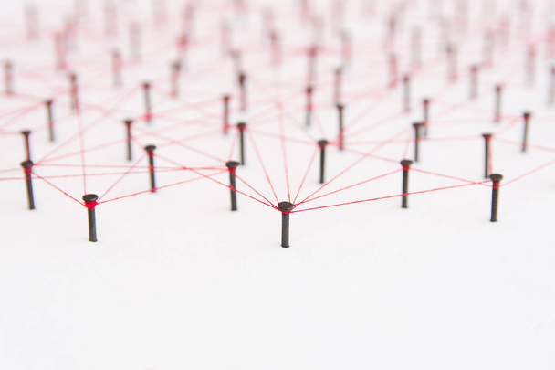 Varlıklar, sosyal medya, İletişim Ağı, iki ağ arasındaki bağlantı bağlantı. Kopyalama alanı ile siyah çivi ve kırmızı iplik tarafından oluşturulan birbirine bağlı beyaz kağıt üzerinde ağ simülasyonu - Fotoğraf, Görsel