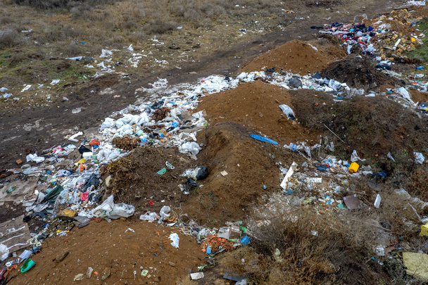 Εναέρια άποψη από ένα μεγάλο σωρό από σκουπίδια. Σωρός από σκουπίδια σε μια παράνομη χωματερή στοιχειακό ή σε χώρους υγειονομικής ταφής, πολλά οικιακά απόβλητα πλαστικές σακούλες μπροστά από το σπίτι. Χώρους υγειονομικής ταφής, περιβαλλοντικών αποβλήτων - Φωτογραφία, εικόνα