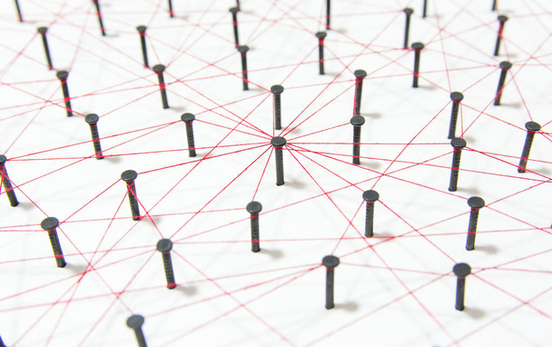 Verknüpfung von Einheiten, sozialen Medien, Kommunikationsnetzen, die Verbindung zwischen den beiden Netzwerken. Netzwerksimulation auf weißem Papier, das durch schwarzen Nagel und roten Faden miteinander verbunden ist - Foto, Bild