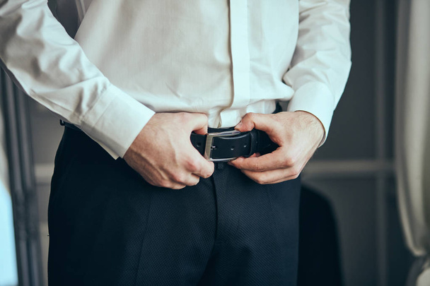 Businessman putting on a belt, fashion and clothing concept,groom getting ready in the morning before ceremony - Foto, afbeelding